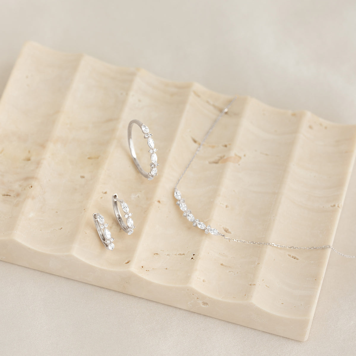 Delicate set featuring Marquise and Round Diamond Ring White Gold - Aurelia with matching earrings and necklace on beige tray