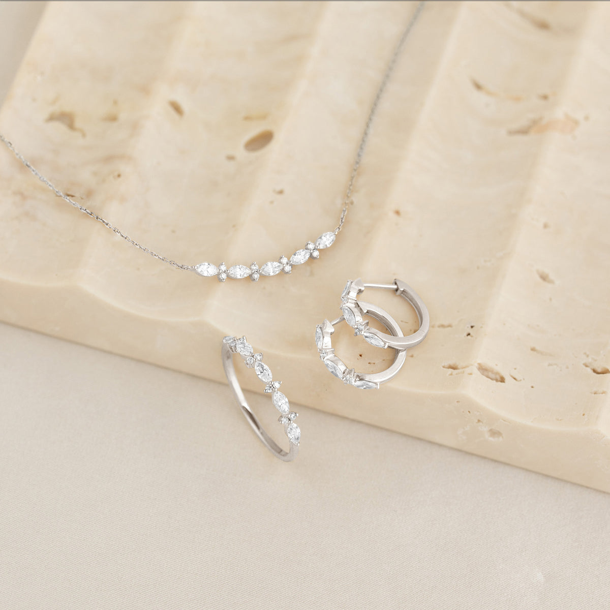 Marquise and Round Diamond Necklace White Gold - Noelia displayed with matching diamond hoop earrings and ring on stone surface