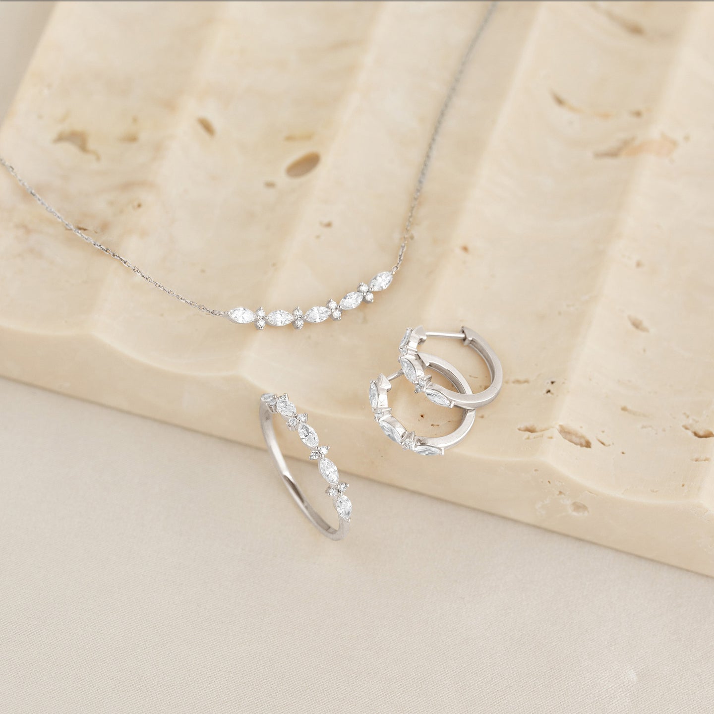 Marquise and Round Diamond Necklace White Gold - Noelia displayed with matching diamond hoop earrings and ring on stone surface
