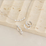 Marquise and Round Diamond Necklace White Gold - Noelia displayed with matching diamond hoop earrings and ring on stone surface