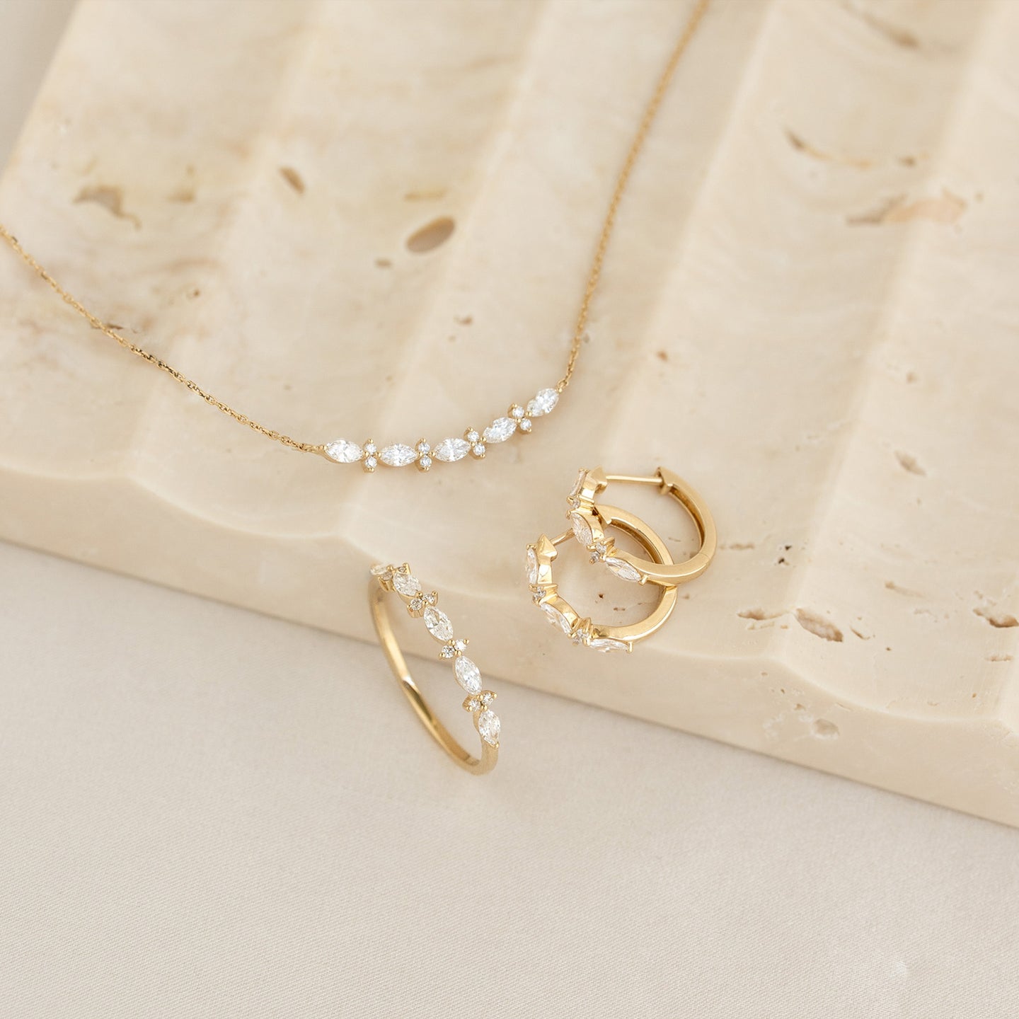 Marquise and Round Diamond Necklace 14k Gold - Noelia displayed with matching gold and diamond hoop earrings and ring on stone surface