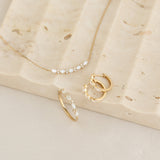 Marquise and Round Diamond Necklace 14k Gold - Noelia displayed with matching gold and diamond hoop earrings and ring on stone surface