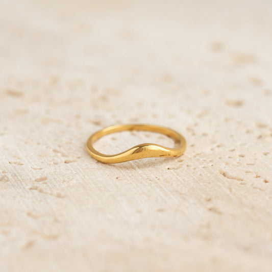 Close-up of an Organic Wavy Ring - Bea in gold vermeil resting on a textured neutral surface