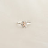 Close-up of Sunburst Morganite Halo Ring White Gold - Evelina with oval morganite and diamond halo on beige background
