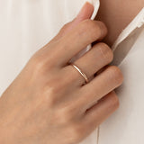 Close-up of a hand wearing the Round Rose Gold Band - Marni on the ring finger against a white fabric background