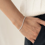 Close-up of a wrist wearing the Diamond Tennis Bracelet White Gold (1.62 ct tw) - Mirella with a soft beige background