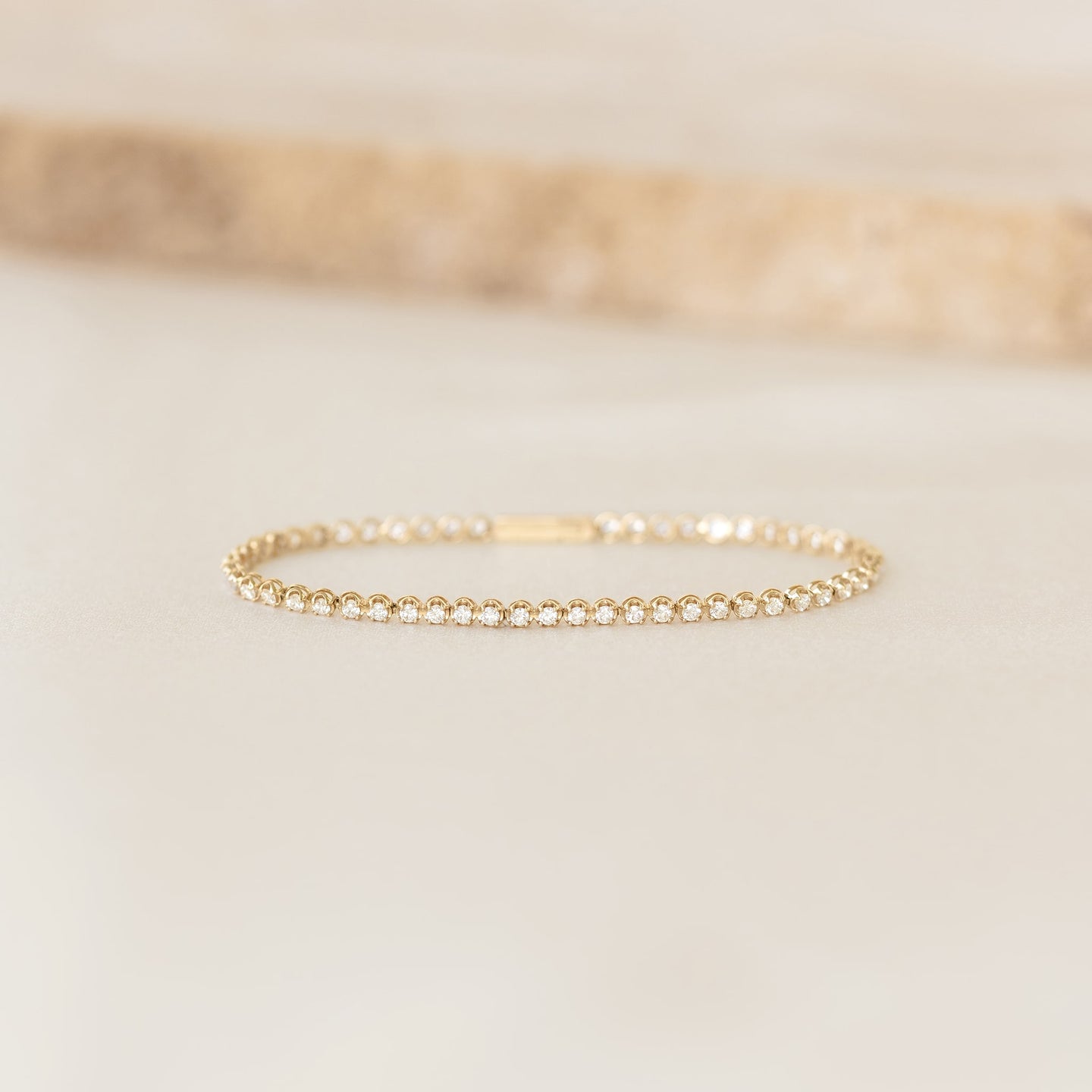 Diamond Tennis Bracelet 14k Gold (1.501 ct tw) - Mirella displayed on a soft beige surface with natural lighting