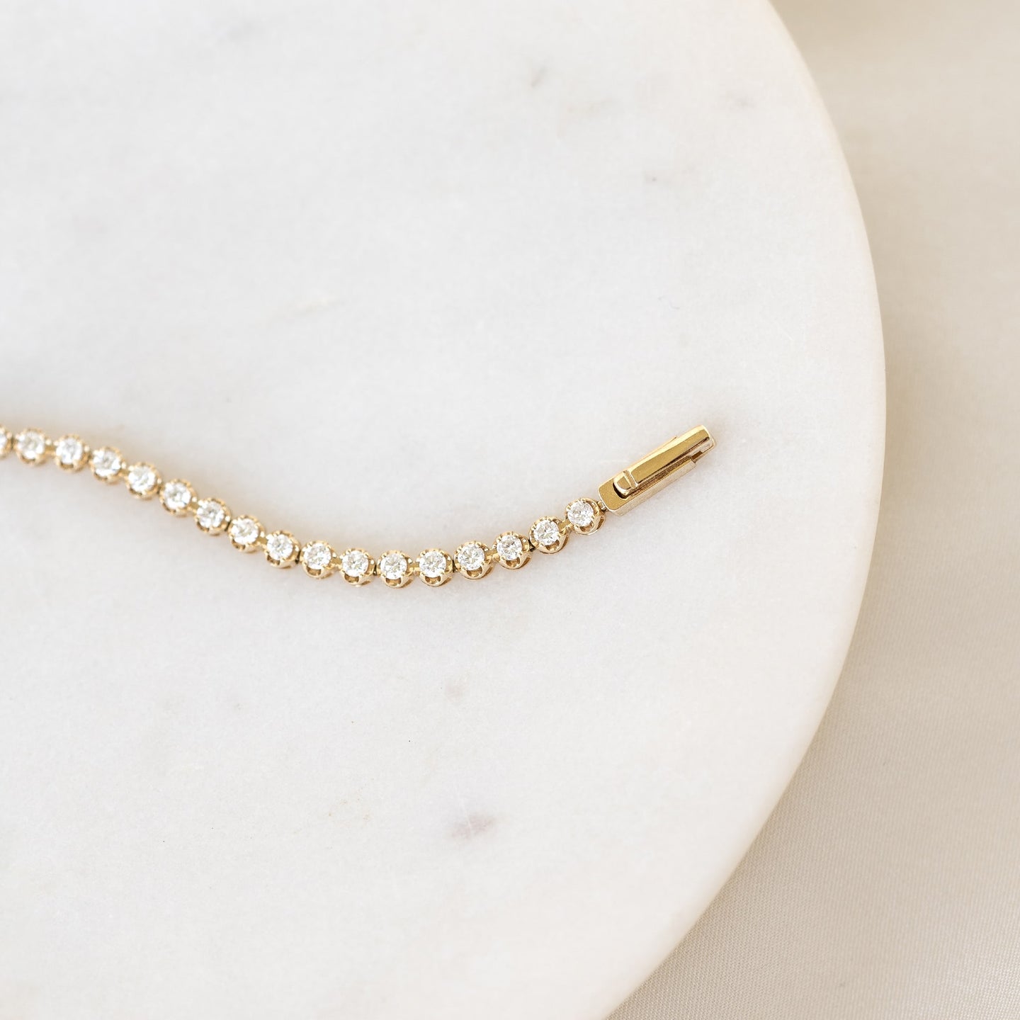 Close-up of Diamond Tennis Bracelet 14k Gold (1.62 ct tw) - Mirella with round diamonds on white marble surface