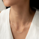 Close-up of a woman wearing the Marquise and Round Diamond Necklace 14k Gold - Noelia with a white top and neutral background