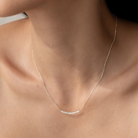 Close-up of a woman wearing the Marquise and Round Diamond Necklace White Gold - Noelia on her bare neck against a neutral background