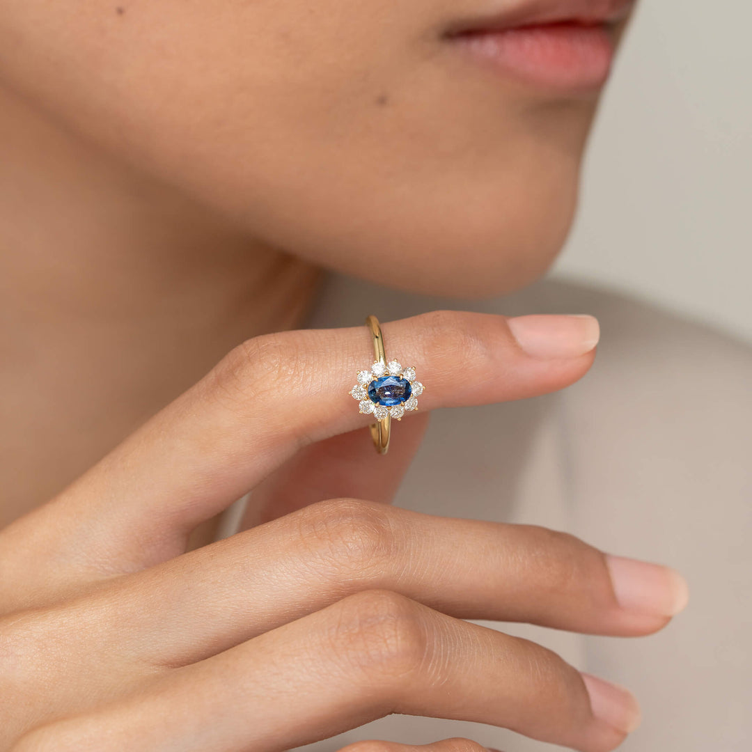The 14k Yellow Gold ring is worn on the index finger, which is gently raised toward the person's chin.