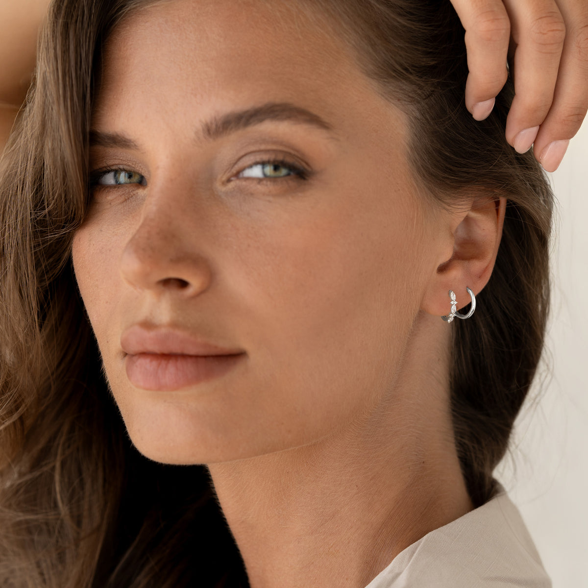 Close-up of a woman wearing Marquise and Round Diamond Huggie Earrings White Gold - Zoya with natural makeup and soft light