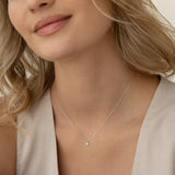Close-up of a woman wearing a Diamond Pendant Necklace White Gold - Atiana on a delicate white gold chain against a neutral background
