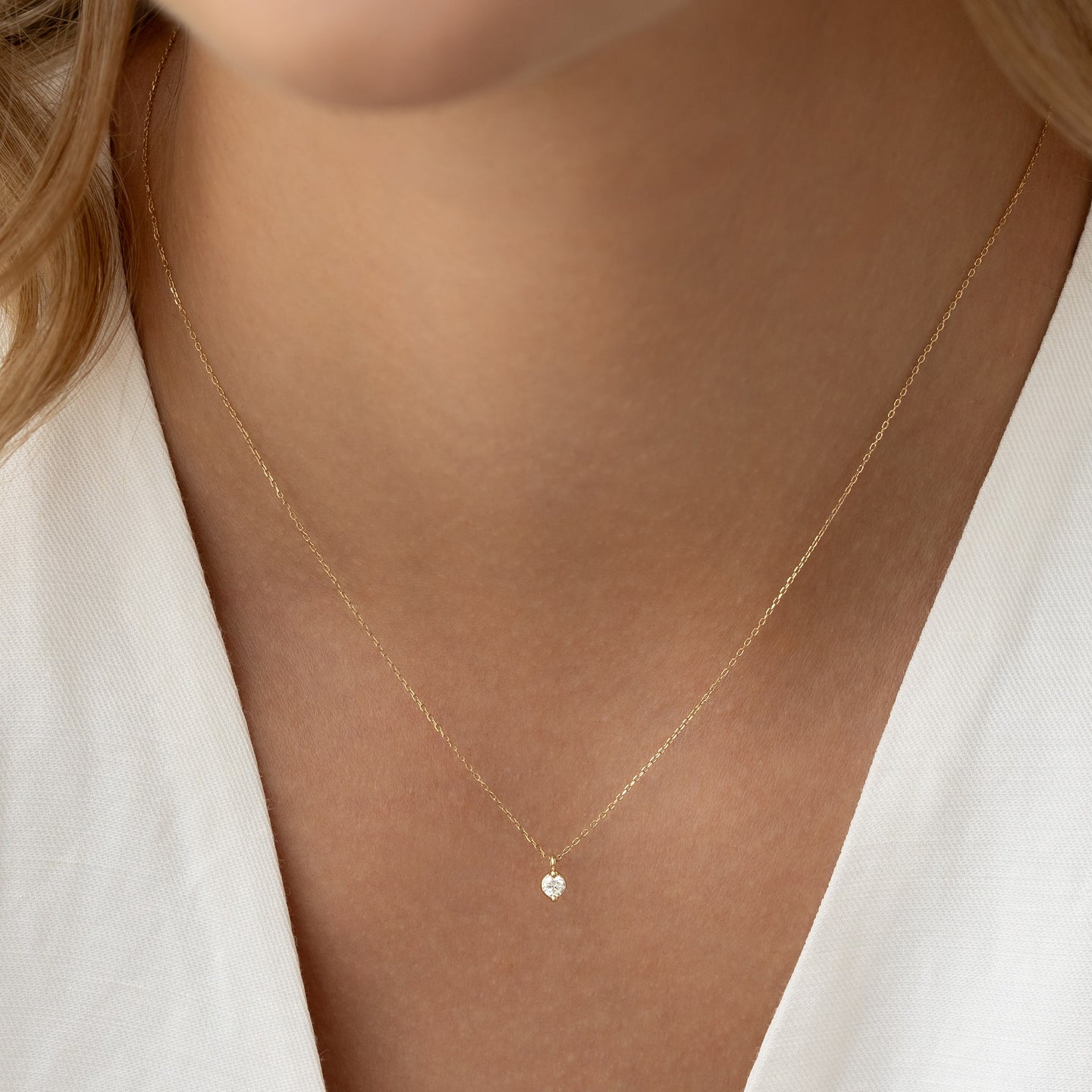 Close-up of a woman wearing the Diamond Pendant Necklace 14k Gold - Atiana with a delicate chain on bare skin
