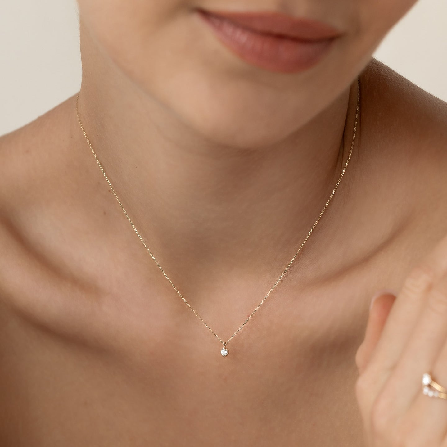 Close-up of a woman wearing the Diamond Pendant Necklace 14k Gold - Atiana with a delicate chain and single round diamond pendant
