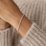 Close-up of a wrist wearing the Tennis Bracelet Silver - Audrey with sparkling cubic zirconia stones on a soft beige sweater