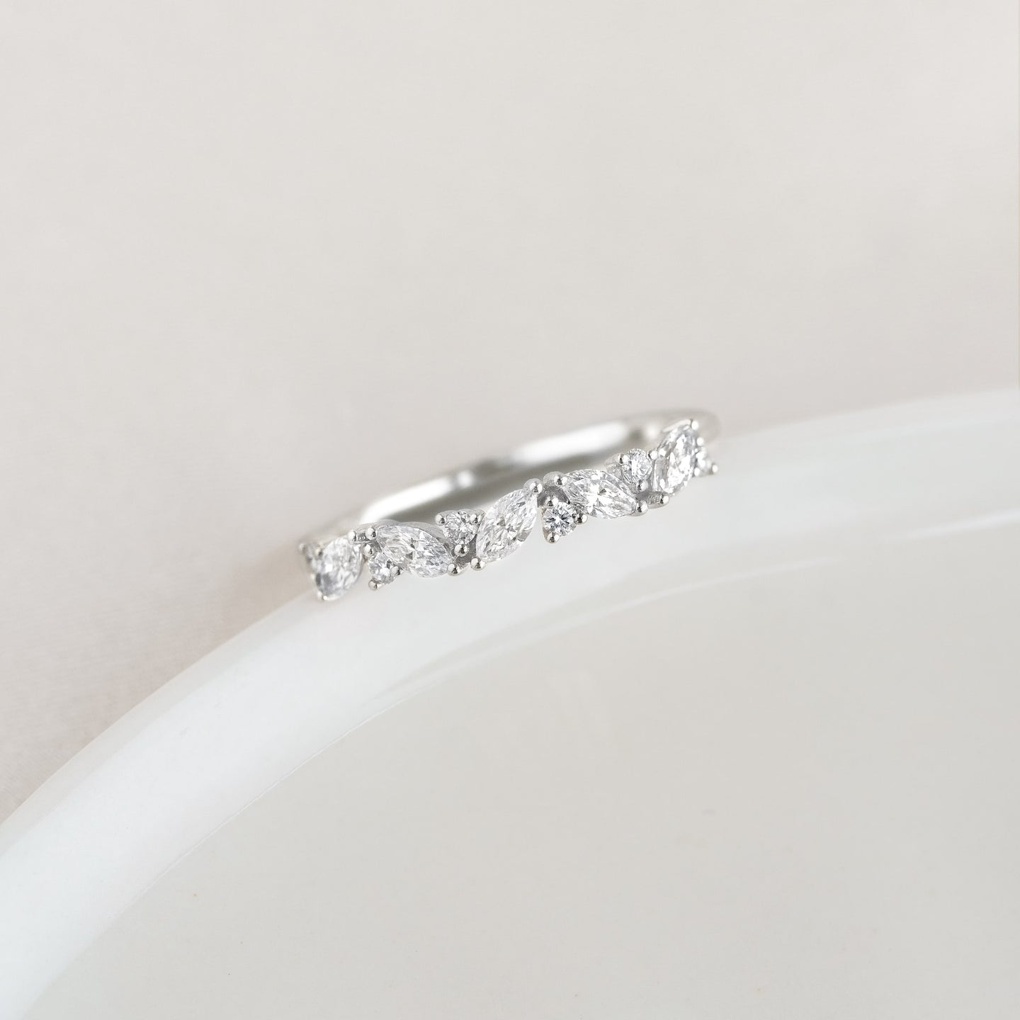 Close-up of the Marquise and Round Diamond Ring White Gold - Celia resting on a smooth white surface with soft lighting