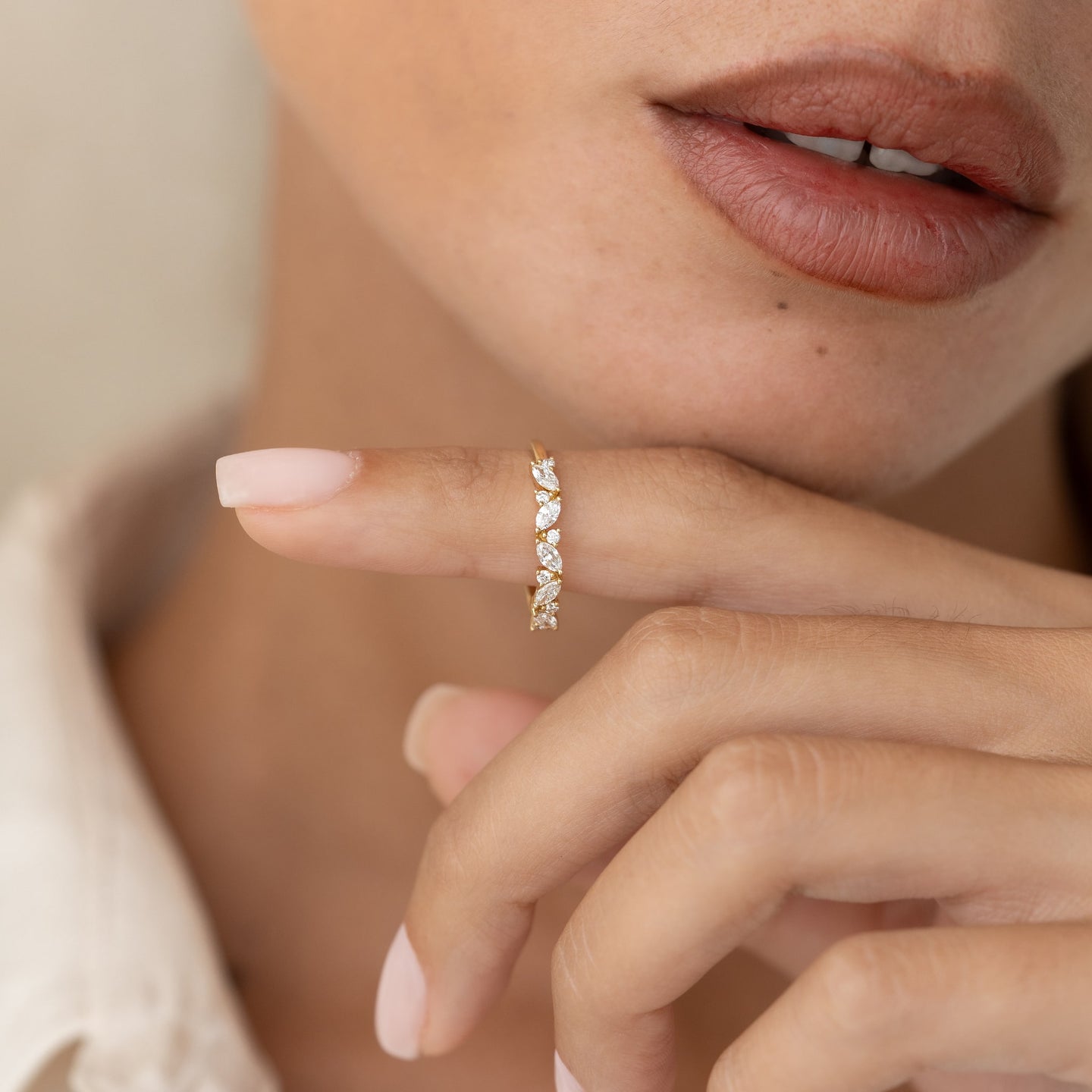 Close-up of a woman holding the Marquise and Round Diamond Ring 14k Gold - Celia delicately on her finger against a neutral background