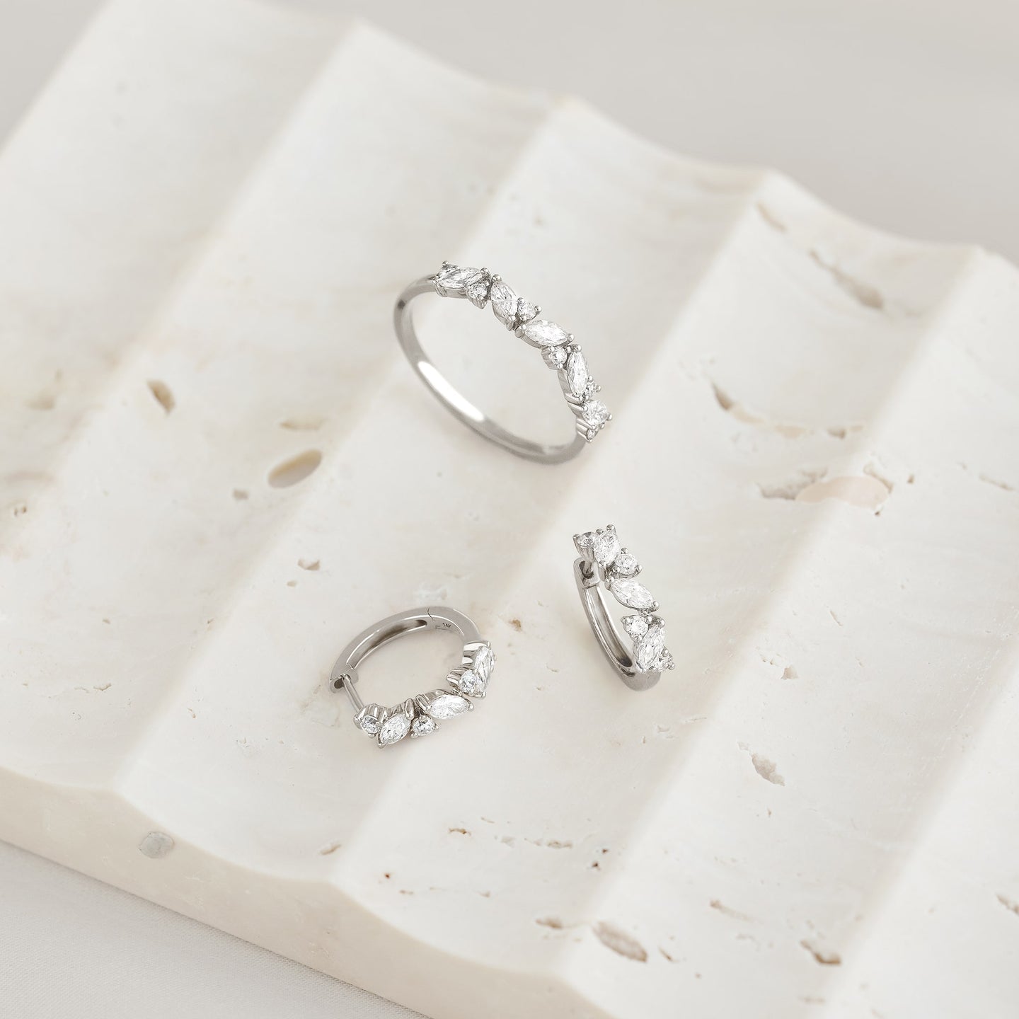 Close-up of Marquise and Round Diamond Ring White Gold - Celia displayed with matching earrings on textured white surface