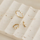 Close-up of Marquise and Round Diamond Ring 14k Gold - Celia and matching earrings on textured beige stone surface