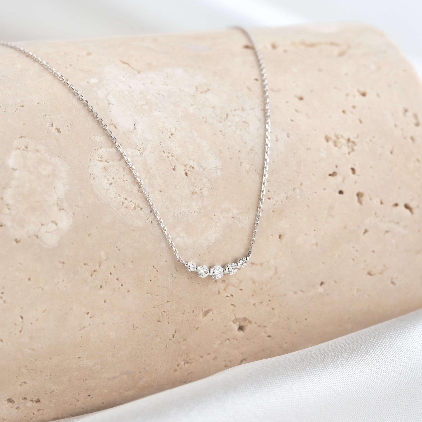 Close-up of Diamond Curved Bar Necklace White Gold - Elodie featuring five graduated diamonds on a delicate white gold chain