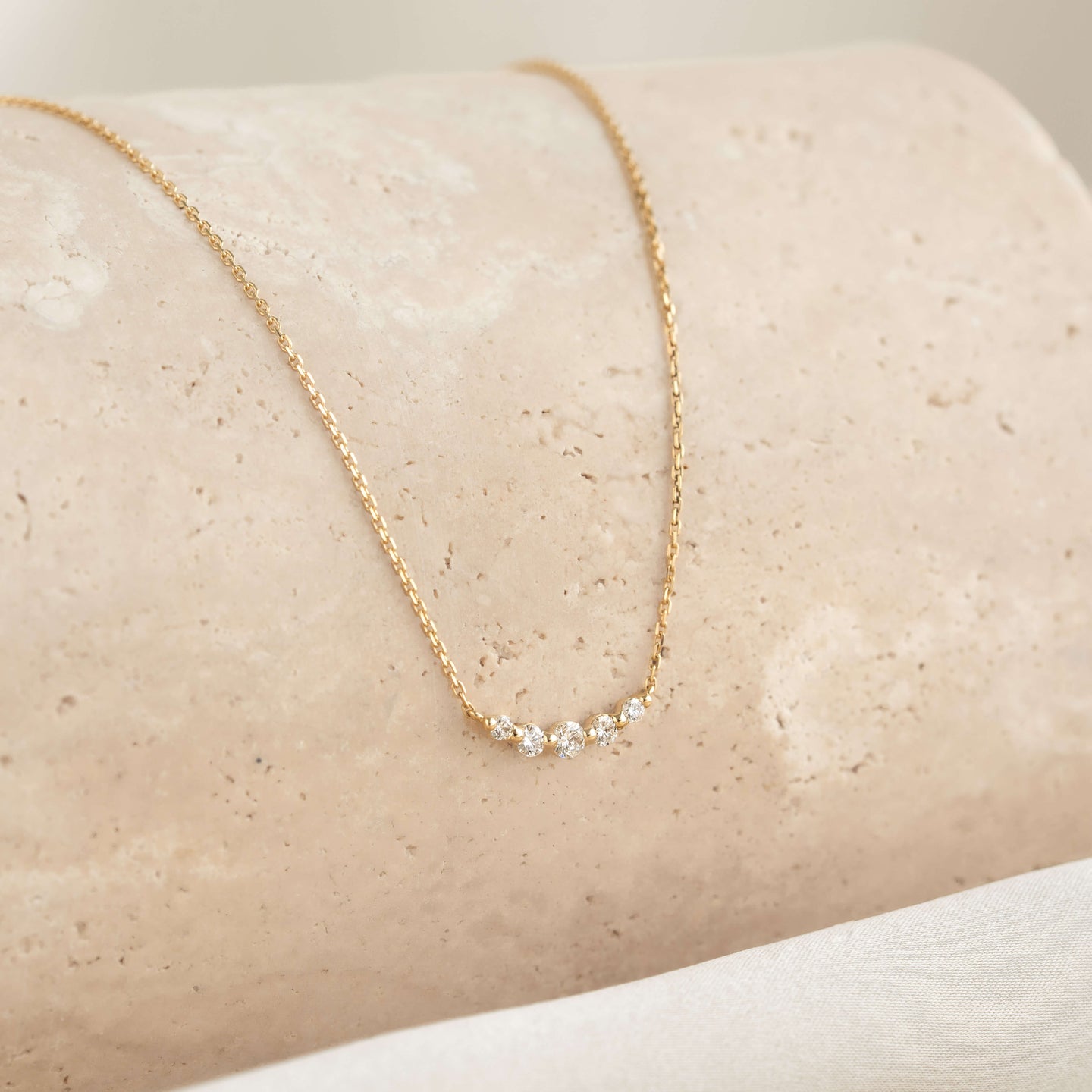 Close-up of the Diamond Curved Bar Necklace 14k Gold - Elodie featuring five graduated diamonds on a delicate gold chain