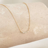 Close-up of the Diamond Curved Bar Necklace 14k Gold - Elodie featuring five graduated diamonds on a delicate gold chain