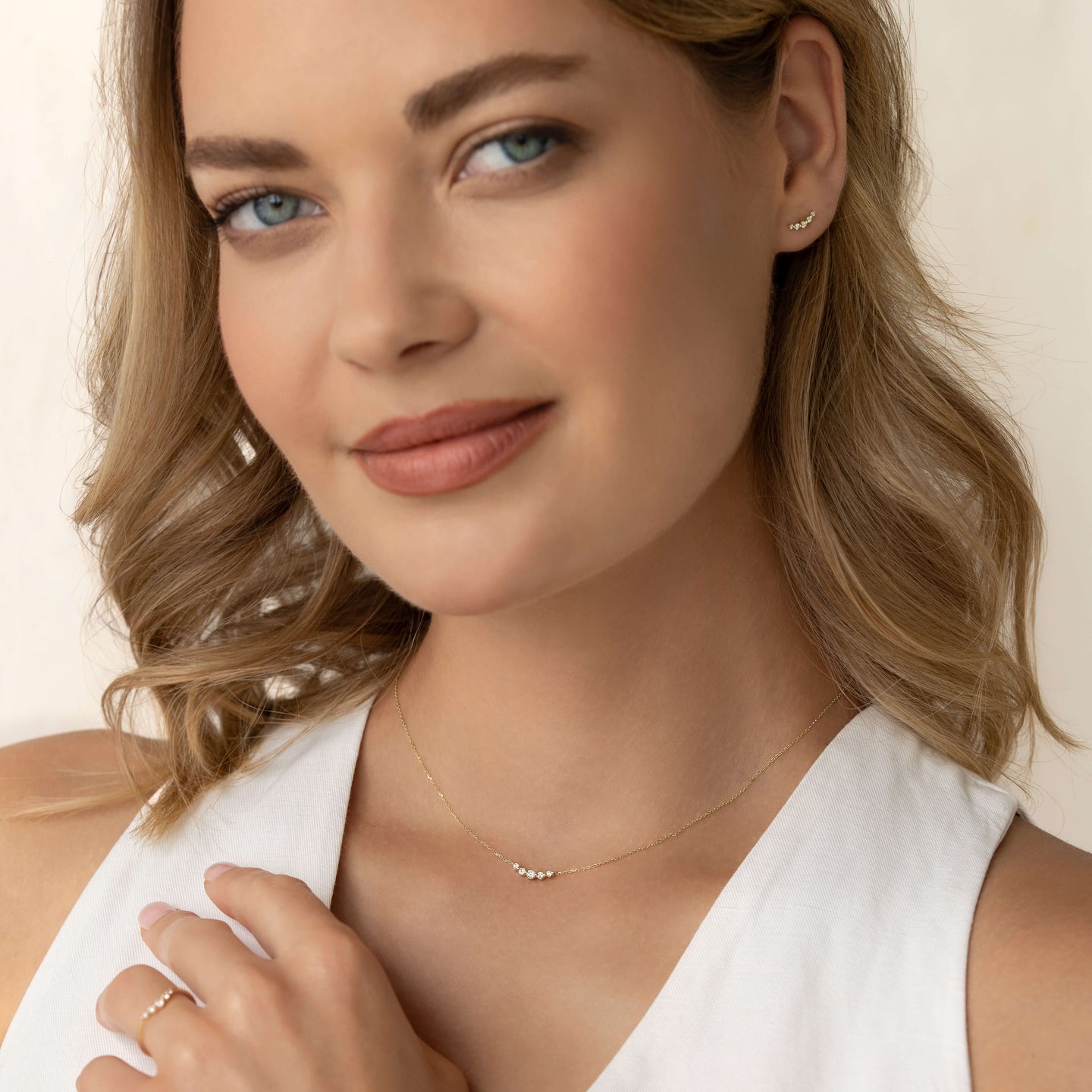 Close-up of a woman wearing the Diamond Curved Bar Necklace 14k Gold - Elodie with matching gold earrings and ring