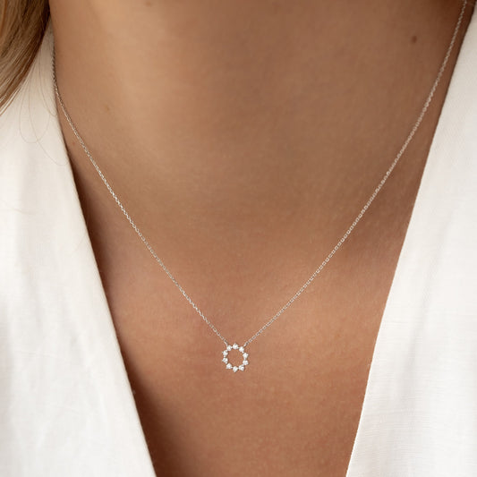Close-up of a woman wearing a Diamond Sun Necklace White Gold - Leda with delicate round diamonds on a fine chain