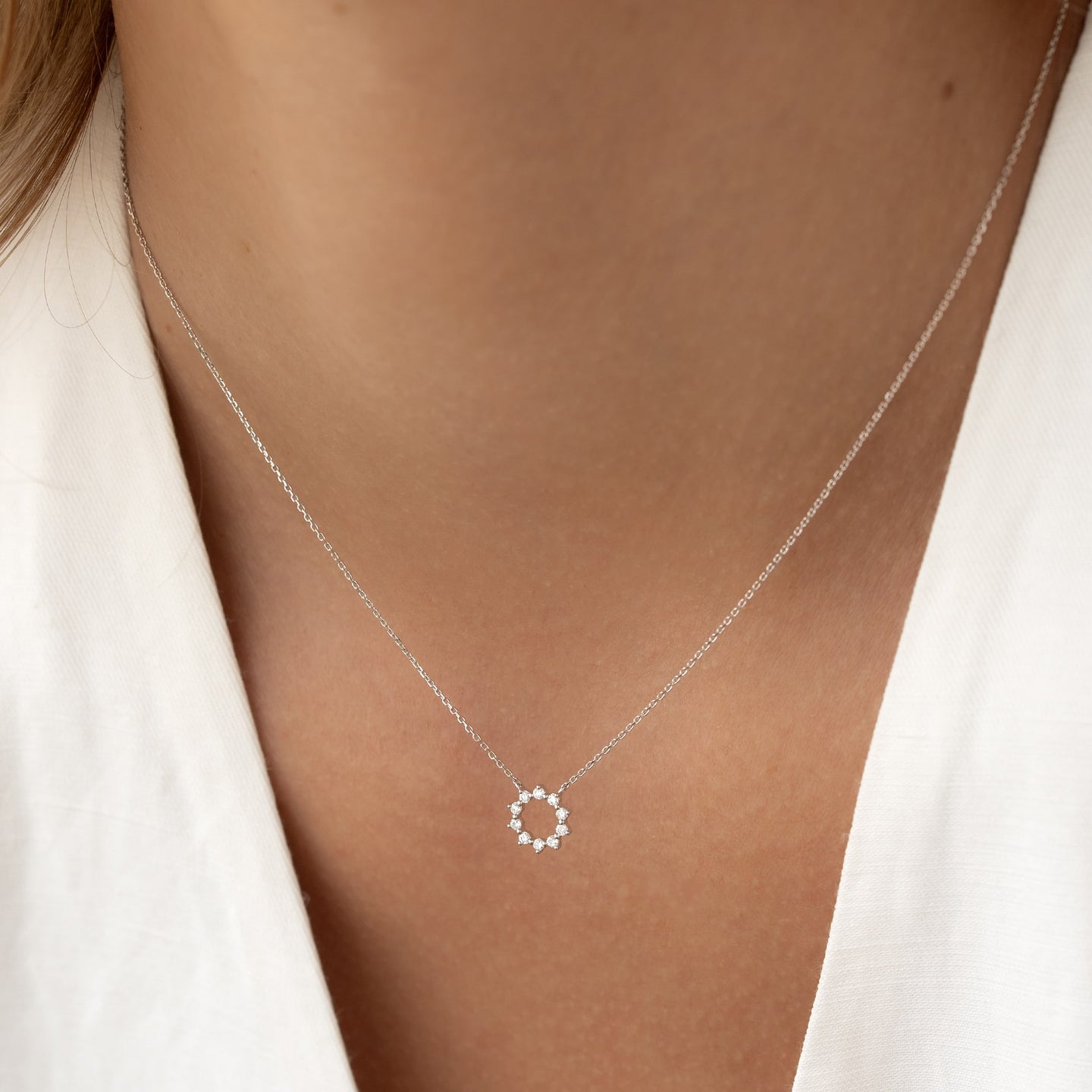 Close-up of a woman wearing a Diamond Sun Necklace White Gold - Leda with delicate round diamonds on a fine chain