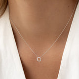 Close-up of a woman wearing a Diamond Sun Necklace White Gold - Leda with delicate round diamonds on a fine chain