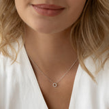 Close-up of a woman wearing the Diamond Sun Necklace White Gold - Leda with a delicate sun pendant on a white top background
