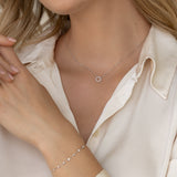 Close-up of a woman wearing the Diamond Sun Necklace White Gold - Leda with a delicate bracelet and cream blouse