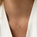 Close-up of a woman wearing the Diamond Sun Necklace 14k Gold - Leda with a delicate diamond sun pendant on a gold chain