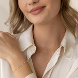 Close-up of a woman wearing the Diamond Sun Necklace 14k Gold - Leda with delicate 14k gold chain and diamonds
