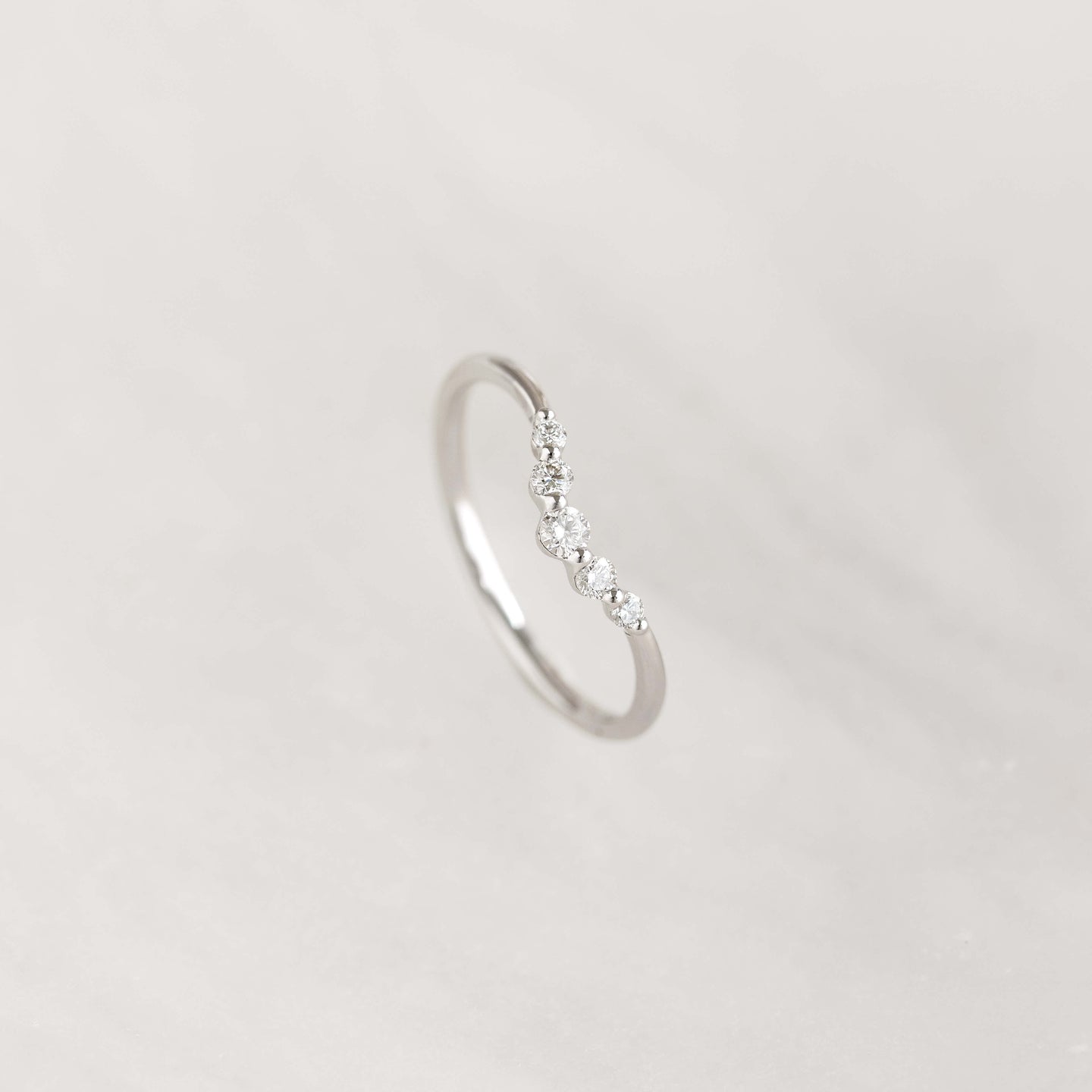 Close-up of the Graduated Diamond V Ring White Gold - Liora featuring five sparkling diamonds on a sleek band