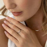 Close-up of a woman wearing the Graduated Diamond V Ring White Gold - Liora on her hand with a matching necklace visible