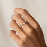 Close-up of a hand wearing the Graduated Diamond V Ring White Gold - Liora with five graduated diamonds on a white gold band
