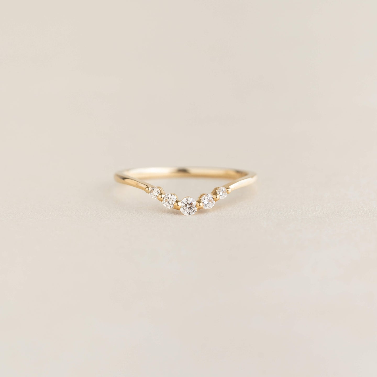 Close-up of the Graduated Diamond V Ring 14k Gold - Liora with five diamonds on a delicate gold band on a neutral background