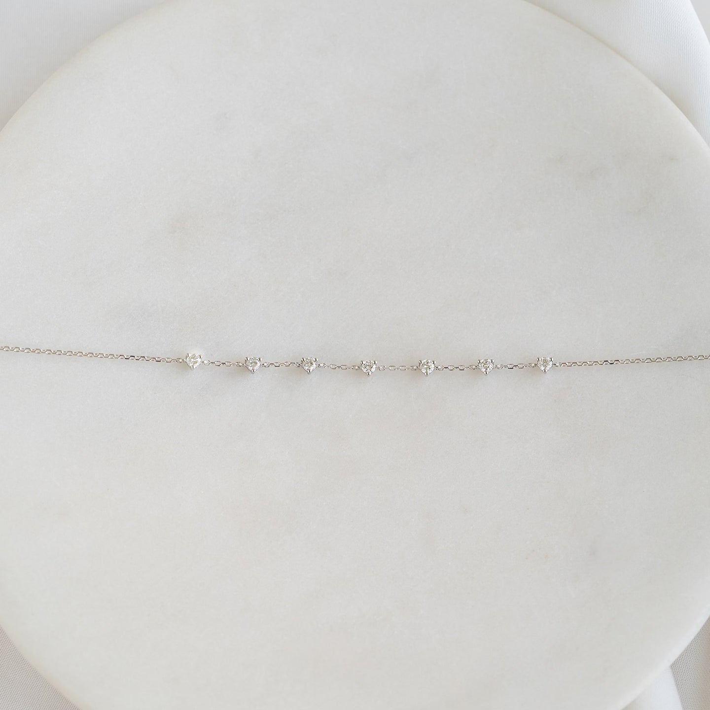 Close-up of Diamond Bracelet White Gold - Lyra featuring seven round diamonds on a delicate white gold chain against a soft white background