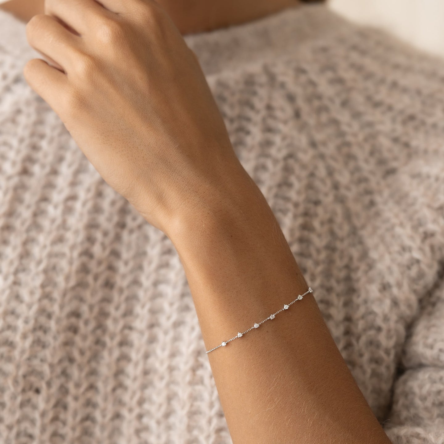 Close-up of a wrist wearing the Diamond Bracelet White Gold - Lyra with seven small diamonds on a delicate chain