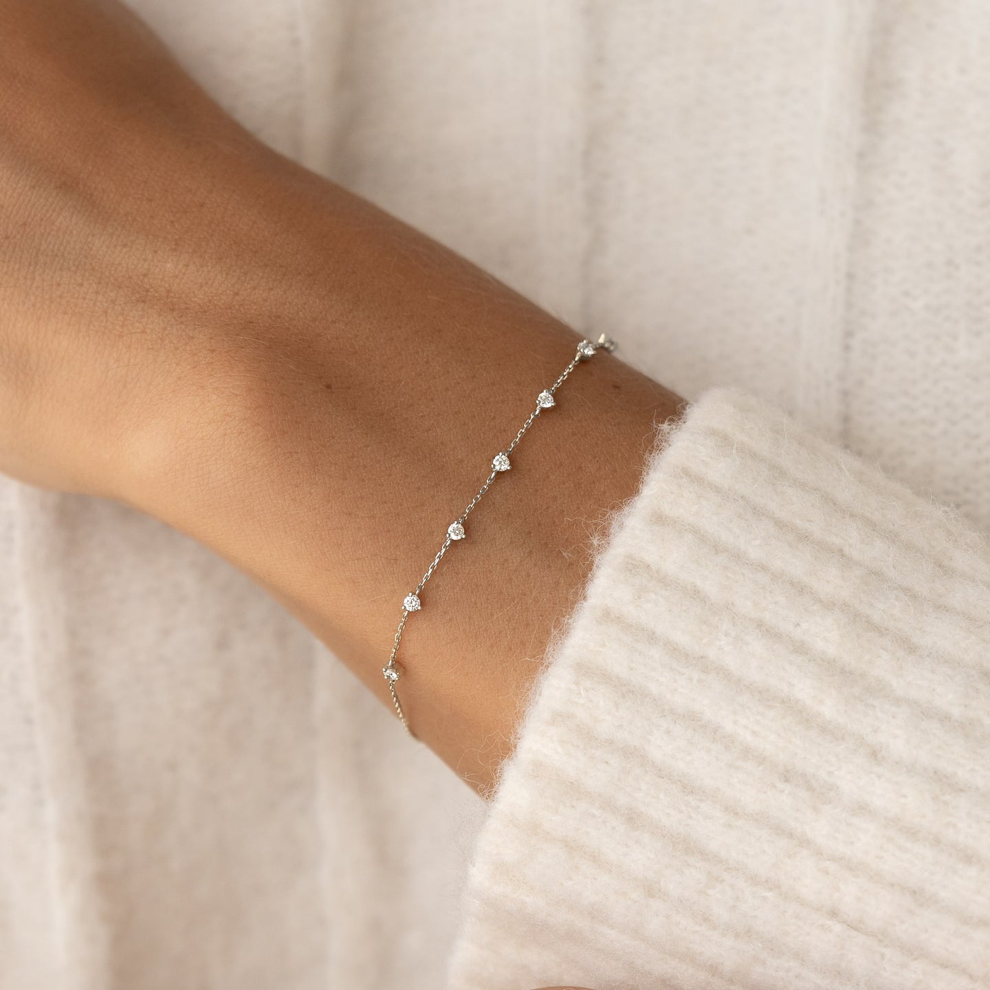 Close-up of a wrist wearing the Diamond Bracelet White Gold - Lyra with seven small round diamonds on a delicate chain