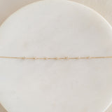 Close-up of Diamond Bracelet 14k Gold - Lyra with seven small diamonds on delicate gold chain on a white marble surface