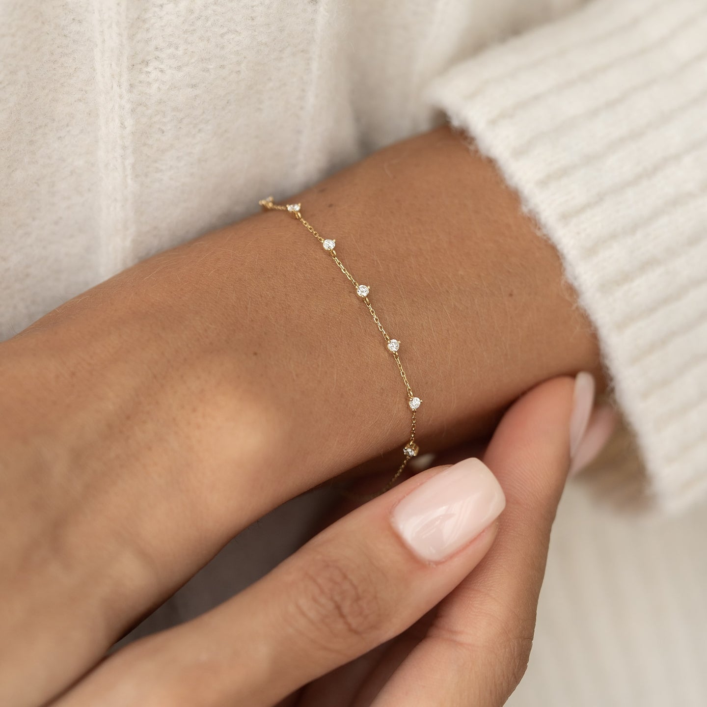 Close-up of a wrist wearing the Diamond Bracelet 14k Gold - Lyra with seven round diamonds on a delicate gold chain