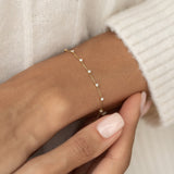 Close-up of a wrist wearing the Diamond Bracelet 14k Gold - Lyra with seven round diamonds on a delicate gold chain