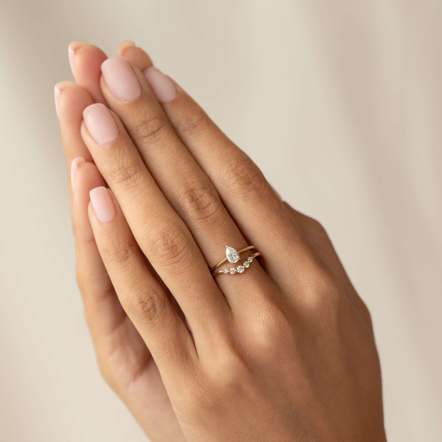 Close-up of a hand wearing the Graduated Diamond V Ring 14k Gold - Liora with polished nails against a neutral background