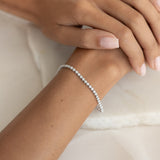 Close-up of a wrist wearing the Diamond Tennis Bracelet White Gold (1.62 ct tw) - Mirella on a soft fabric background