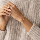 Woman wearing Diamond Tennis Bracelet 14k Gold (1.501 ct tw) - Mirella on wrist with beige knitted sweater background