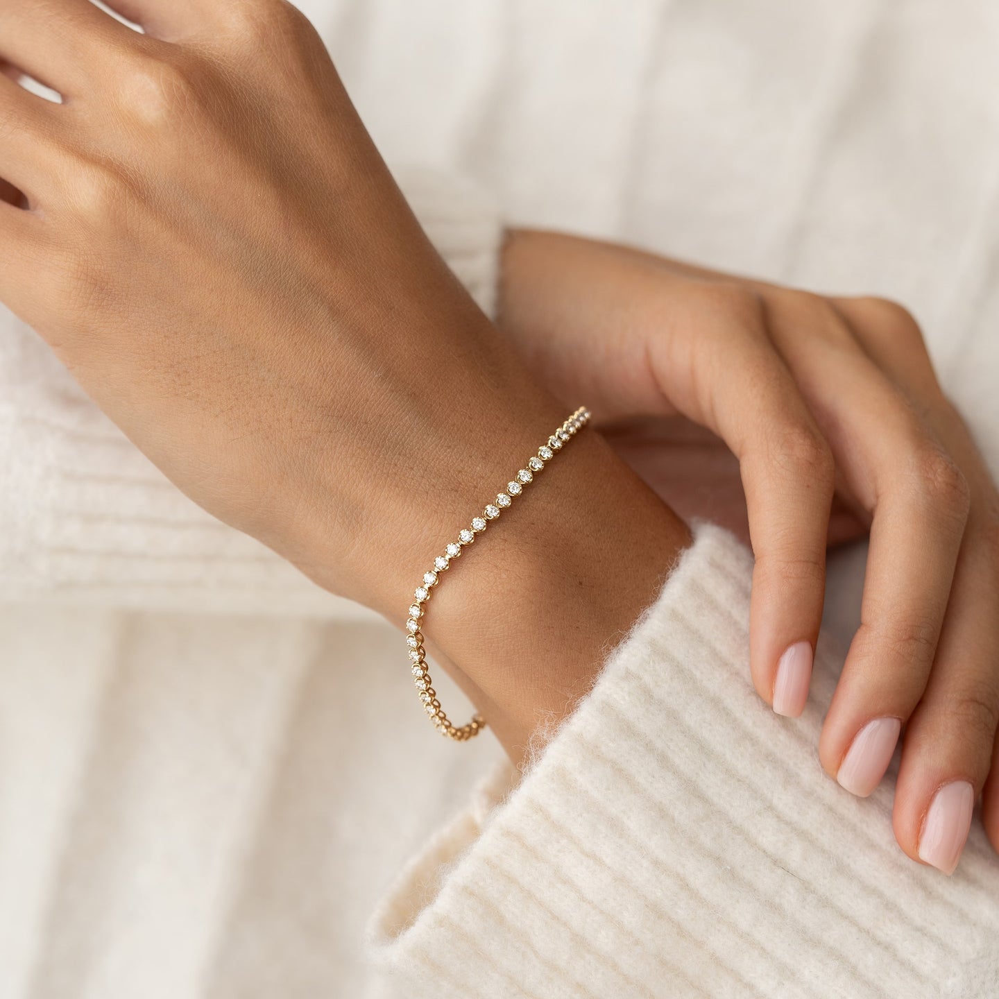 Close-up of a wrist wearing Diamond Tennis Bracelet 14k Gold (1.62 ct tw) - Mirella with round diamonds on a soft cream background