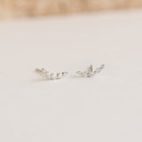 Close-up of Diamond Climber Stud Earrings White Gold - Rhea with six sparkling diamonds on a light surface